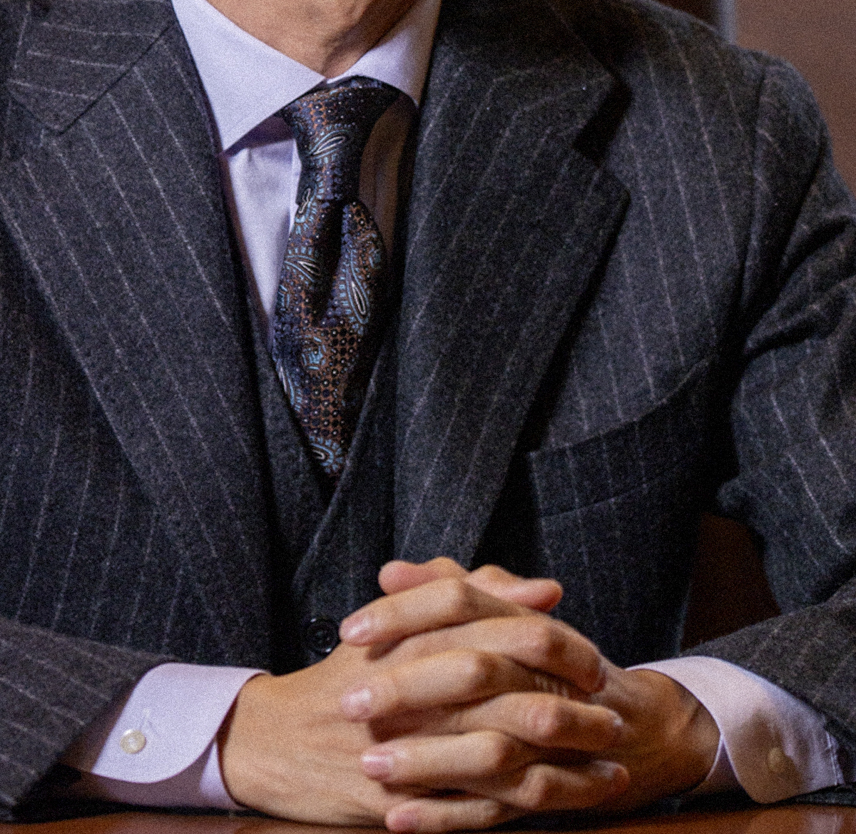 煉瓦の壁の前で振り返るグレースーツの男性