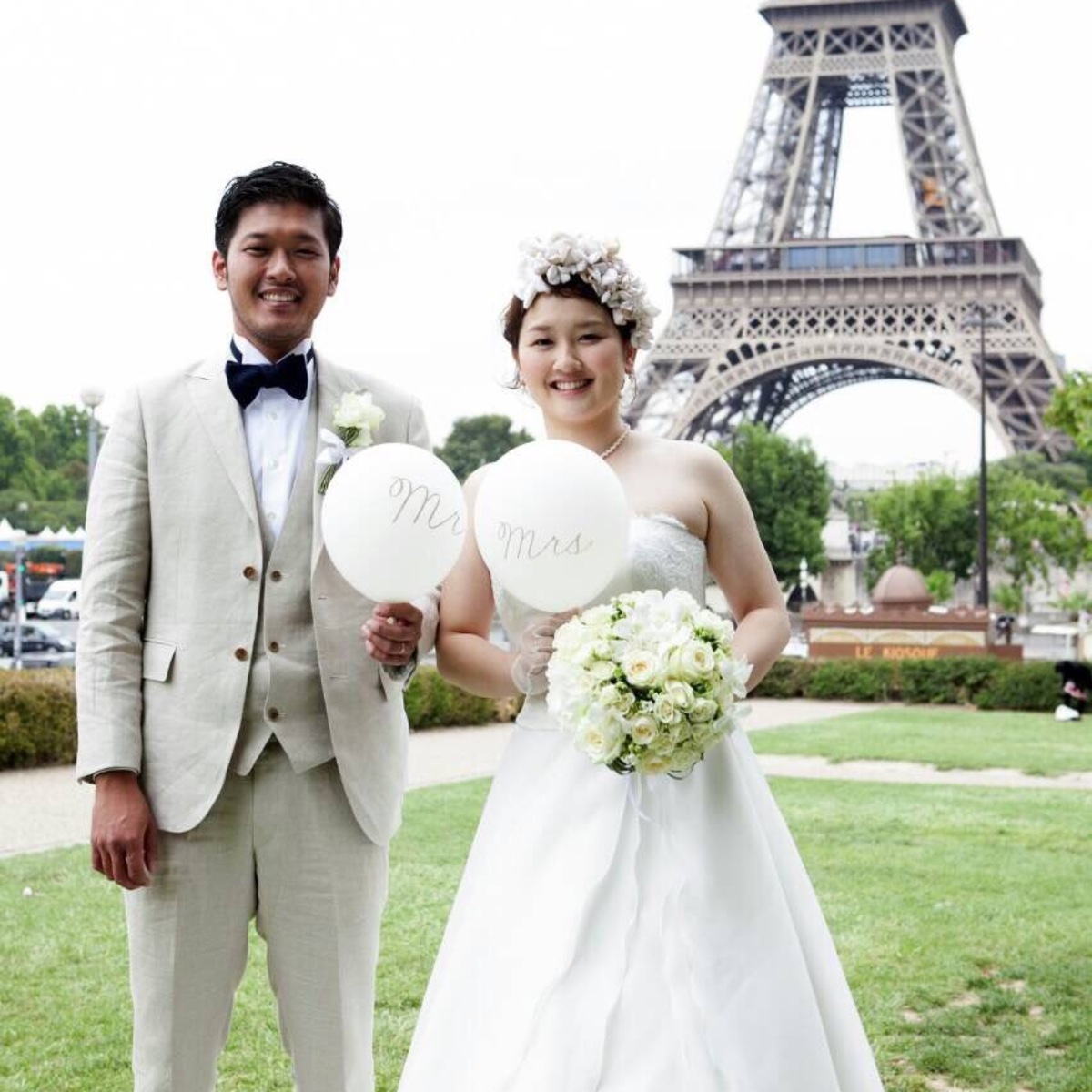 パリのエッフェル塔を背景にMr.&Mrsのボードを掲げる新郎新婦